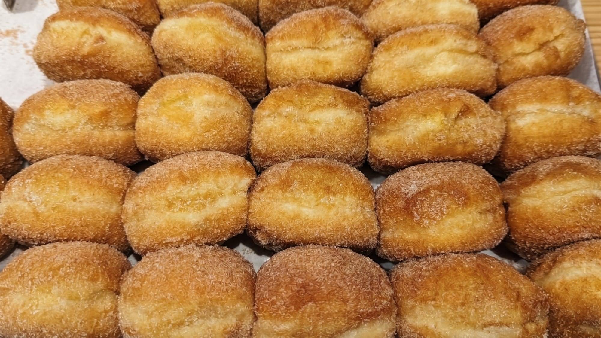 Tabuleiro de bolas de Berlim sem creme, douradas e passadas por açúcar e canela