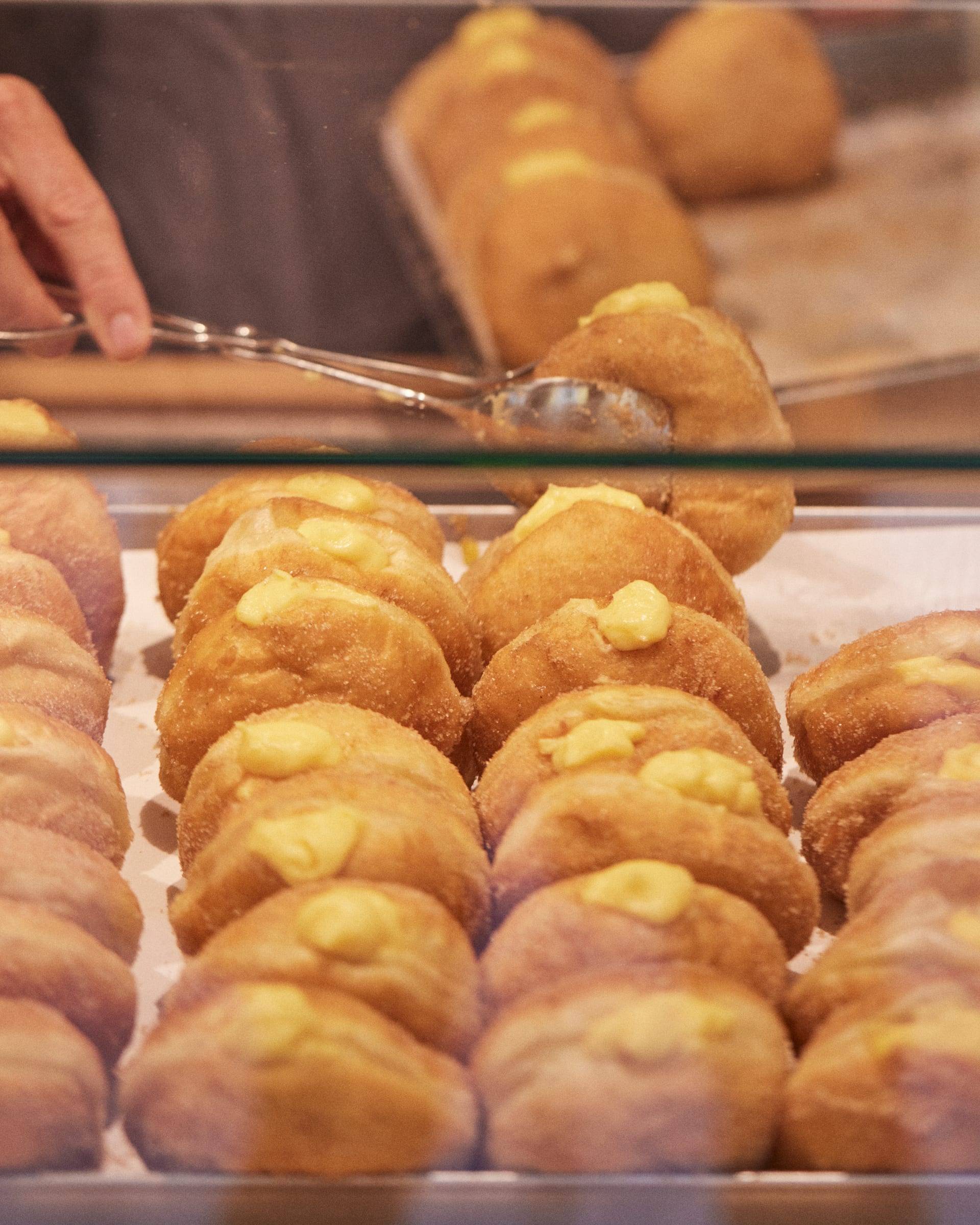 Bola de Berlim with egg custard piped visibly on top rather than hidden inside